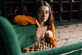 Portrait of attractive young woman wearing elegant eyeglasses making chess move with knight piece sitting in floor Royalty Free Stock Photo