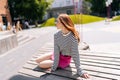 Portrait of attractive young woman wearing skirt sitting resting on wooden bench in public park on summer sunny day Royalty Free Stock Photo