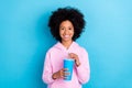 Portrait of attrctive trendy cheerful girl drinking beverage free time rest isolated over vibrant blue color background
