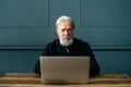 Portrait of authority bearded senior elegant businessman sitting at wooden table with laptop computer at home office Royalty Free Stock Photo