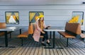 Portrait of awesome girl, wearing coat and yellow beret. Sitting on the train station read a book and looking straight. Autumn