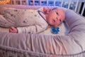 Portrait of a baby boy aged 1 month lying with his eyes open in a crib. Caucasian child in the children bedroom on the bed Royalty Free Stock Photo