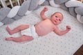 Portrait of a baby boy aged 1 month lying with his eyes open in a crib. Caucasian child in the children bedroom on the bed Royalty Free Stock Photo