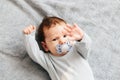 Portrait of baby boy angry, furious, frowning and agressive lying on a bed. Childrens emotions