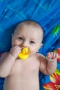 Portrait of baby boy holding yellow rubber duck in mouth after bathing