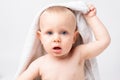 A young boy is holding a white towel on his head with one hand. Baby after bathing. On a white background. Royalty Free Stock Photo