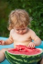 Portrait of baby child outdoors. One year old baby boy eating watermelon slice in the garden. Royalty Free Stock Photo