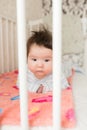 Portrait of a baby in the crib. High angle portrait of a beautiful baby with a finger in his mouth, lying on the bed, his eyes Royalty Free Stock Photo