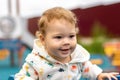 Portrait baby girl boy in white hoodie outdoor. Happy smiling Caucasian child 1 year old for a walk on the playground Royalty Free Stock Photo