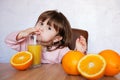 Portrait of a baby girl funny drinks a fresh juice on a table Royalty Free Stock Photo