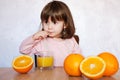 Portrait of a baby girl funny drinks a fresh juice on a table Royalty Free Stock Photo