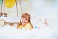 Portrait of a baby girl lying on a cloud next to a basket of balloon in the clouds, traveling and flying in dreams