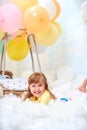 Portrait of a baby girl lying on a cloud next to a basket of balloon in the clouds, traveling and flying in dreams