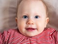 Portrait of a baby girl, 8 months old, looking at the camera, laughing, top view, close-up. A mischievous, beautiful girl with Royalty Free Stock Photo