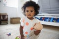 Portrait Of Baby Girl Playing With Doll In Playroom