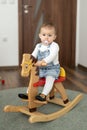 Portrait of baby girl playing on wooden rocking horse. Childhood, game at home concept Royalty Free Stock Photo