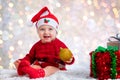 Portrait of a baby girl with a Santa hat holding a Christmas ornament Royalty Free Stock Photo