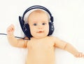 Portrait baby listens to music in headphones lying on the bed