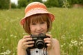 Portrait of a baby photographer a little girl with a camera on the background of nature. Royalty Free Stock Photo