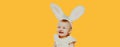 Portrait of baby with rabbit ears crying on yellow background