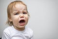 Portrait of a baby toddler child crying. Kid opened his mouth wide, in which fangs erupt and saliva flows. The child has