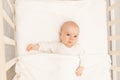 Portrait of a baby in a white crib. Interior of the children`s room and bedding for children. A cute little girl is lying in her Royalty Free Stock Photo