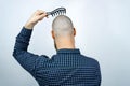 Portrait of back bald man head holding a comb in his hand. The concept of hair loss and hair transplantation Royalty Free Stock Photo