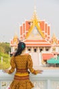 Portrait back side Asian woman in a yellow Thai patterned standing in front of a Buddhist Chruch while traveling in Asia