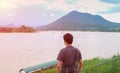 Portrait back side of asian young men casual wear is looking into boat at the river and mountain. Royalty Free Stock Photo