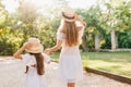 Portrait from back of tall tanned woman leading daughter down the street. Blonde slim lady holding hands with little Royalty Free Stock Photo