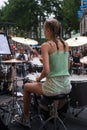 Portrait on back view of blond teenager playing drums in the street