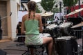 Portrait on back view of blond teenager playing drums in the street