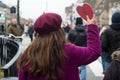 woman wearing purple coat and purple woolen hat taking a wooden heart in hand