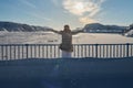 Portrait from back of warmly dressed woman in defocus standing in front of sea looking far away looking at winter rough