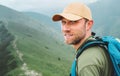 Portrait of backpacker man in baseball cap walking by the foggy cloudy weather mountain range path with backpack. Active sports Royalty Free Stock Photo