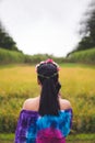 Portrait backside an Asian woman in a patterned color dress with flowers on her hair, she is using a cell phone in front of a rice Royalty Free Stock Photo