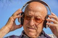 Portrait of a bald elderly man listening to music with headphones. dementia therapy