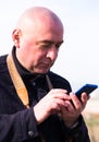 Portrait of bald elderly man looking at smartphone