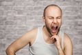 Portrait a bald guy in a white t-shirt sits on a chair and thinks about problems with money, loneliness, payments, work and