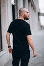 Portrait of a bald handsome bearded man in a black t-shirt on the street, who looks away