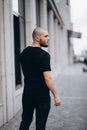 Portrait of a bald handsome bearded man in a black t-shirt on the street, who looks away