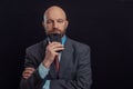 Portrait of bald male business man on dark background. Man in his 40s with grey beard, wearing classic suit, blue shirt, and red Royalty Free Stock Photo