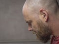 Portrait of a bald man with a beard bowing his head and looking down. side view Royalty Free Stock Photo