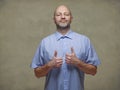 Portrait of a bald man in blue shirt thumbs up gesture. Light color background. The model is in his 40s with short grey beard. Royalty Free Stock Photo