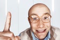 Portrait Bald man with glasses shows, point an index finger and smiles Royalty Free Stock Photo