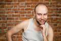 Portrait bald man laughing mockingly at something or someone on brick wall background Royalty Free Stock Photo