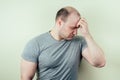 A portrait of a bald man is sad against a gray background. problem of male pattern baldness. sadness, vexation and anger Royalty Free Stock Photo