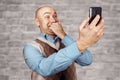 Portrait Bald man talking on the phone and selfie on white brick wall background Royalty Free Stock Photo