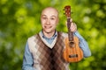 Portrait Bald man with ukulele on green bokeh background Royalty Free Stock Photo