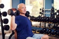 A portrait of senior man in the gym training with dumbbells. People, health and lifestyle concept